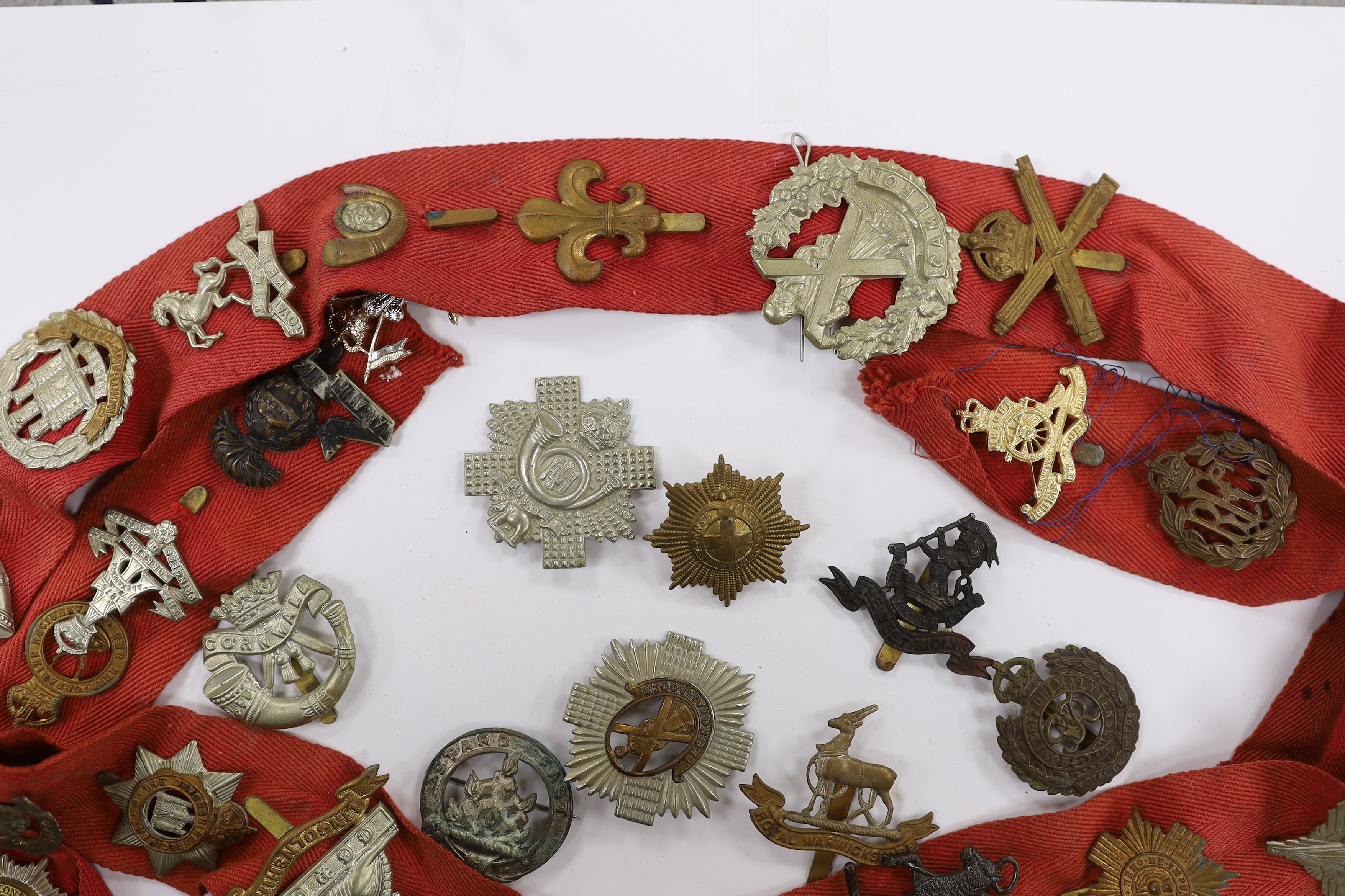 Thirty-two military cap badges, including; The Devonshire Reg., The Buffs, RFC, Royal Artillery, The Royal Sussex Reg. Royal Warwickshire Reg., Cornwall, etc.
